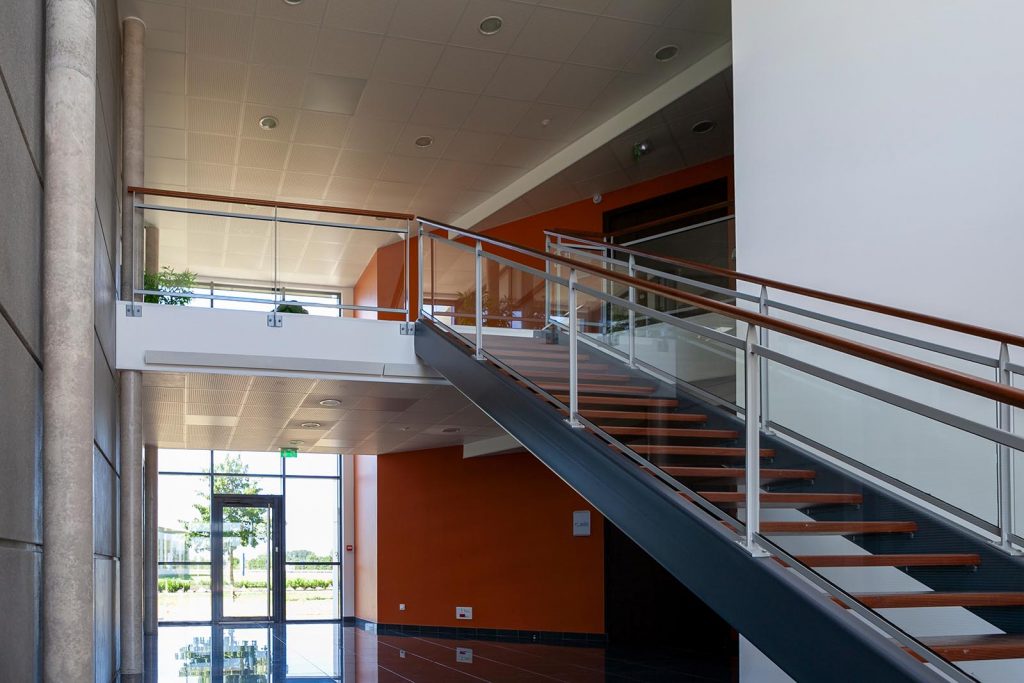 Escalier d'entreprise avec limon acier et garde-corps inox finition main courante bois